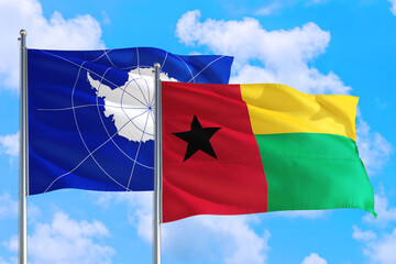 Guinea and Antarctica national flag waving in the windy deep blue sky. Diplomacy and international relations concept.