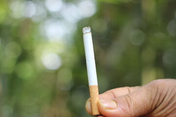 Man hand holding cigarette. Cigarette in hand. Unhealthy lifestyle concept.