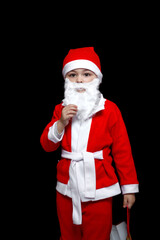 a five-year-old boy in a funny Santa Claus costume stands with a package of gifts. on a black isolated background