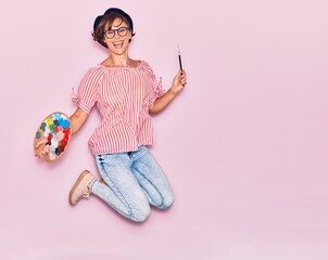 Young beautiful artist woman wearing glasses and beret smiling happy. Jumping with smile on face...