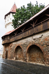 Fototapeta premium Cetatii Street with the Carpenters Tower and a wooden covered gallery that connects with the Potters Tower. Sibiu, Romania.