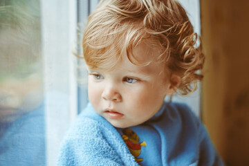 a little boy is sitting by the window