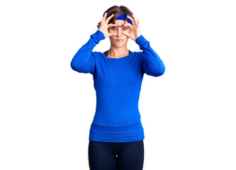 Beautiful young woman with short hair wearing training workout clothes trying to open eyes with fingers, sleepy and tired for morning fatigue