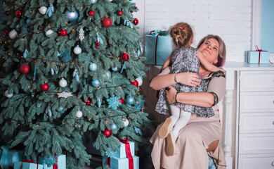 Winter holiday concept. Inspiration and fairy time. Mom and little girl near Christmas tree at holydays. Pretty nice cozy holiday days, magical Christmas time