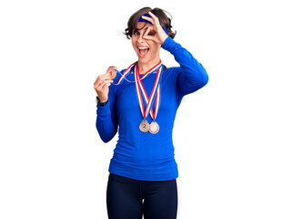 Beautiful young woman with short hair wearing winner medals smiling happy doing ok sign with hand on eye looking through fingers