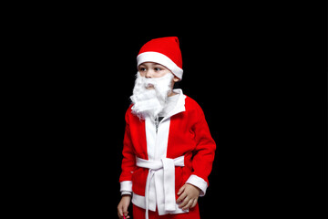 Fototapeta na wymiar a five-year-old boy in a funny Santa Claus costume stands with a package of gifts. on a black isolated background