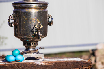 Old samovar with Easter eggs stands on a wooden table.