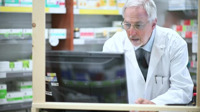 Pharmacist at work with a computer in his store