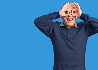 Senior handsome man wearing casual polo doing ok gesture like binoculars sticking tongue out, eyes looking through fingers. crazy expression.