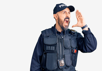 Young handsome man wearing police uniform shouting and screaming loud to side with hand on mouth. communication concept.