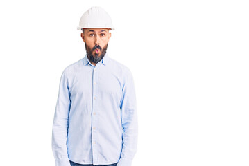 Young handsome man wearing architect hardhat afraid and shocked with surprise expression, fear and excited face.