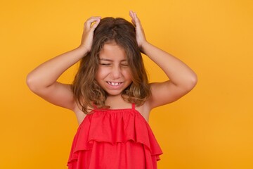 Fototapeta premium young Caucasian girl standing against yellow background suffering from strong headache holding her head with her hands.