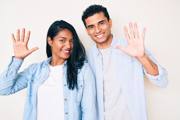 Fototapeta na wymiar Beautiful latin young couple wearing casual clothes showing and pointing up with fingers number ten while smiling confident and happy.