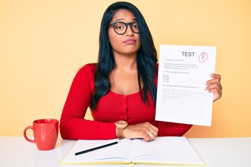 Beautiful latin young woman with long hair showing a failed exam thinking attitude and sober expression looking self confident