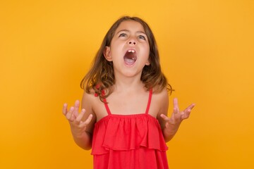 Caucasian young girl standing against yellow background crying and screaming. Human emotions,...