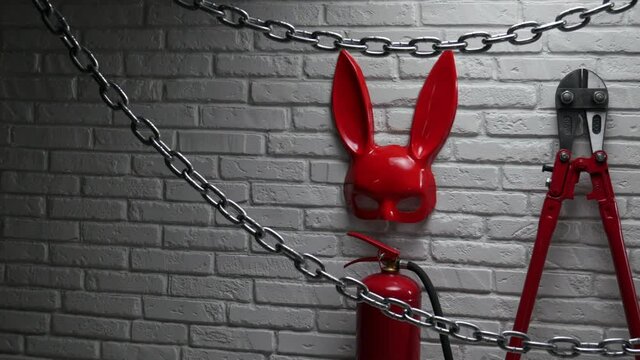 creative design of a fire brick wall with a rabbit mask, fire extinguishers and bolt cutter with a stretched chain