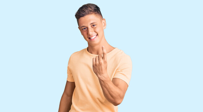 Young handsome man wearing casual clothes beckoning come here gesture with hand inviting welcoming happy and smiling