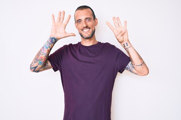 Young handsome man with tattoo wearing casual clothes showing and pointing up with fingers number...