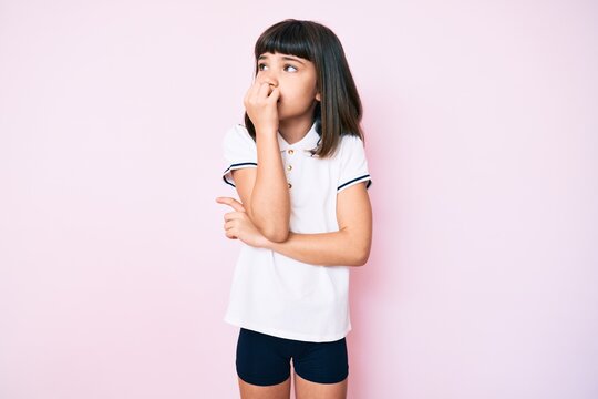 Young little girl with bang wearing sportswear looking stressed and nervous with hands on mouth biting nails. anxiety problem.