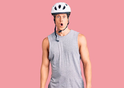 Young handsome man wearing bike helmet afraid and shocked with surprise expression, fear and excited face.