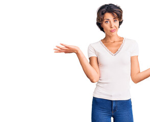 Young beautiful woman wearing casual clothes clueless and confused expression with arms and hands...