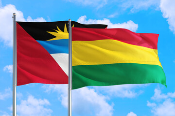 Bolivia and Antigua and Barbuda national flag waving in the windy deep blue sky. Diplomacy and international relations concept.