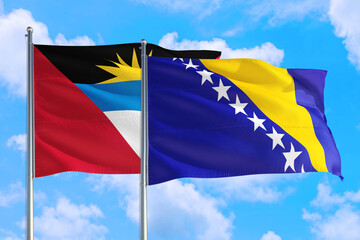 Bosnia Herzegovina and Antigua and Barbuda national flag waving in the windy deep blue sky. Diplomacy and international relations concept.