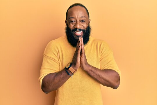 Young african american man wearing casual clothes praying with hands together asking for forgiveness smiling confident.