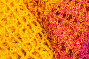 handmade multicolor crochet background in  yellow, orange, pink and purple with double crochet stitches