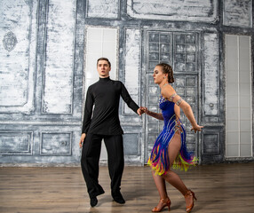 beautiful couple with dance costumes dancing latin dances in the hall