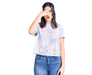Fototapeta premium Young beautiful girl wearing casual t shirt peeking in shock covering face and eyes with hand, looking through fingers with embarrassed expression.