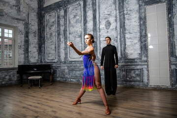 beautiful couple with dance costumes dancing latin dances in the hall