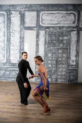 beautiful couple with dance costumes dancing latin dances in the hall