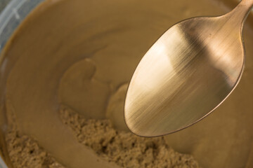 empty bronze colored spoon in front brown chocolate mousse