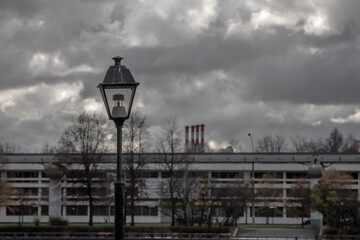 A lonely old lantern against the backdrop of a gloomy autumn sky and cityscape. Cloudy sky. Gray colors