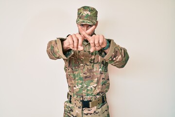Young caucasian man wearing camouflage army uniform rejection expression crossing fingers doing negative sign