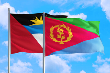 Eritrea and Antigua and Barbuda national flag waving in the windy deep blue sky. Diplomacy and international relations concept.