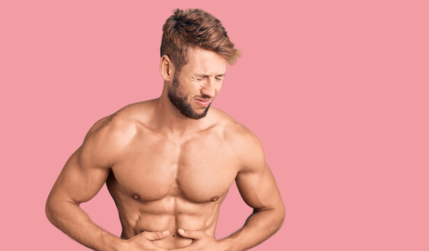 Young caucasian man standing shirtless with hand on stomach because indigestion, painful illness feeling unwell. ache concept.