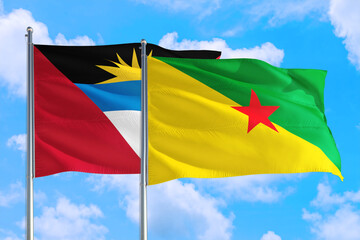 French Guiana and Antigua and Barbuda national flag waving in the windy deep blue sky. Diplomacy and international relations concept.
