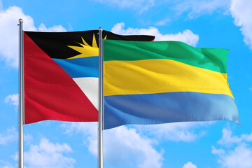 Gabon and Antigua and Barbuda national flag waving in the windy deep blue sky. Diplomacy and international relations concept.