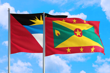 Grenada and Antigua and Barbuda national flag waving in the windy deep blue sky. Diplomacy and international relations concept.