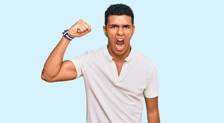 Fototapeta premium Young arab man wearing casual clothes angry and mad raising fist frustrated and furious while shouting with anger. rage and aggressive concept.