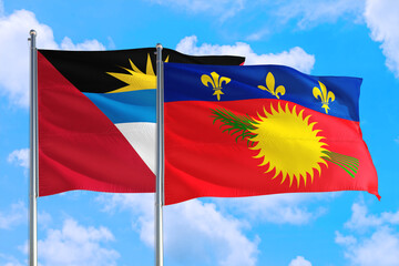 Guadeloupe and Antigua and Barbuda national flag waving in the windy deep blue sky. Diplomacy and international relations concept.