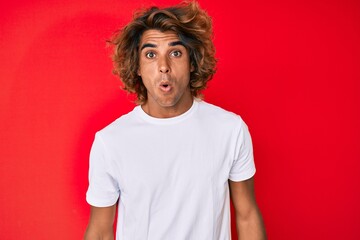 Young hispanic man wearing casual white tshirt scared and amazed with open mouth for surprise, disbelief face