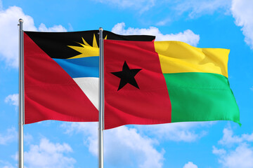 Guinea and Antigua and Barbuda national flag waving in the windy deep blue sky. Diplomacy and international relations concept.