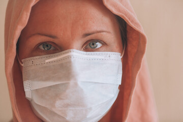 Girl in a protective mask. Portrait of a girl in a mask from the virus and a pink hood