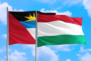 Hungary and Antigua and Barbuda national flag waving in the windy deep blue sky. Diplomacy and international relations concept.