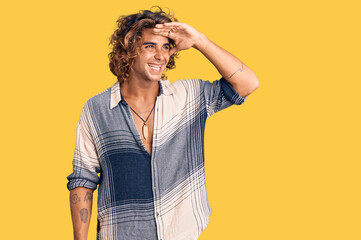 Young hispanic man wearing summer style very happy and smiling looking far away with hand over...