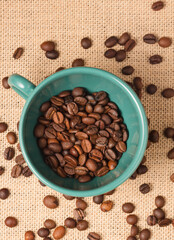 green coffee cup with grains and raffia cloth background
