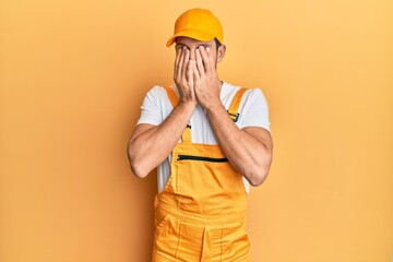 Young handsome man wearing handyman uniform over yellow background rubbing eyes for fatigue and...